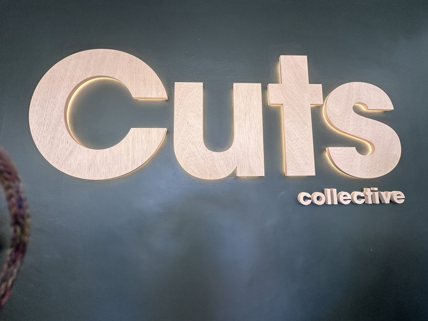 Le logo de Cuts Collective au mur du salon, à Soustons
